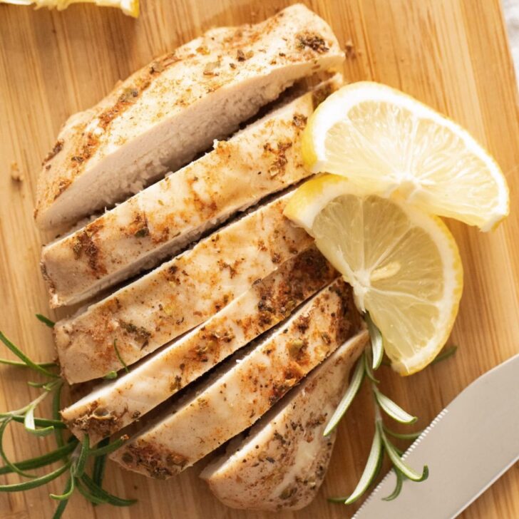 sliced instant pot frozen chicken breast with lemon slices and rosemary.
