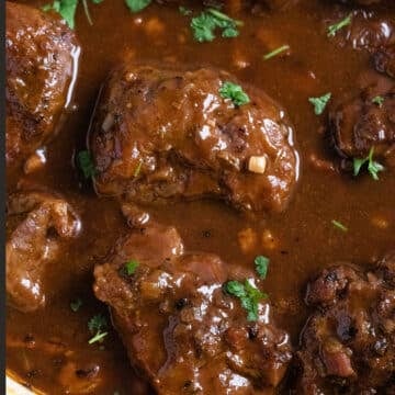 close up pig cheeks braised in a beer sauce.