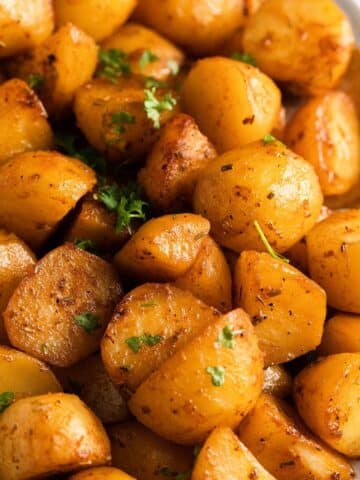 close up of golden slow cooker roast potatoes sprinkled with parsley.