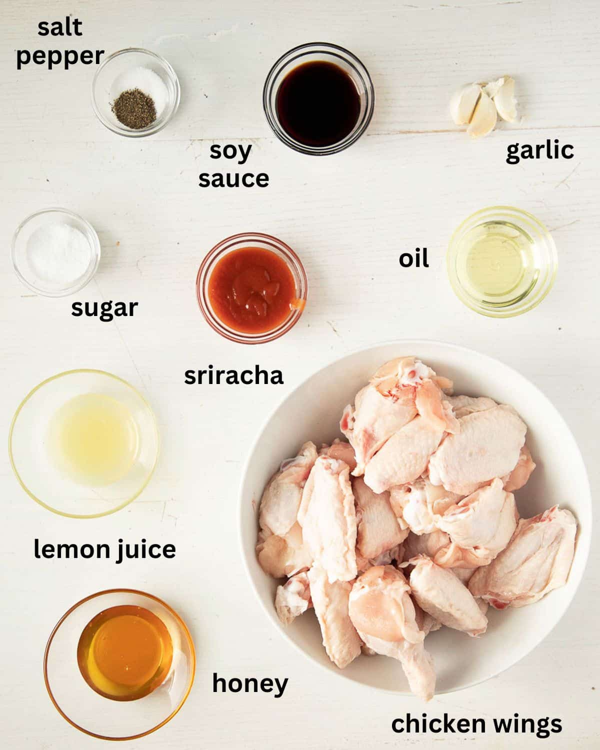 listed ingredients for making baked wings with hot sauce on a table.