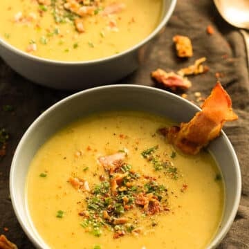 two bowls of potato soup with leeks, with pieces of crispy bacon sticking into the soup.