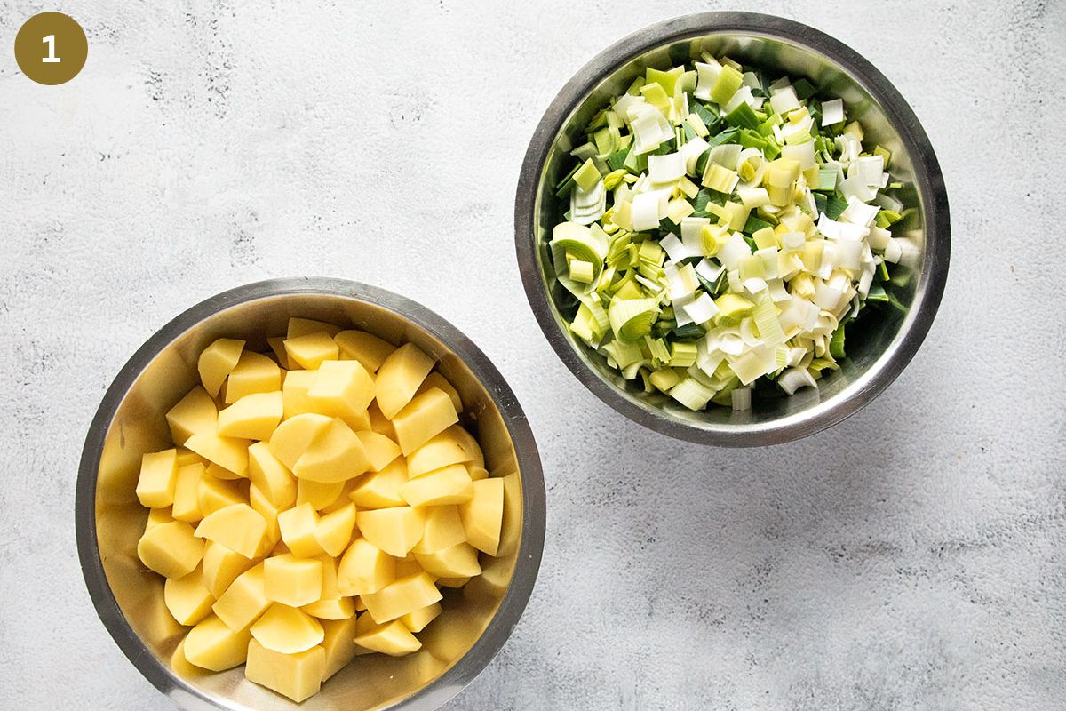 one bowl with chopped potatoes and one bowl with chopped leeks.