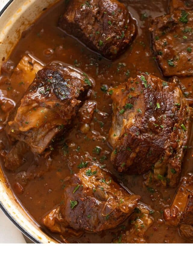 close up of beer braised short ribs in a white dutch oven.