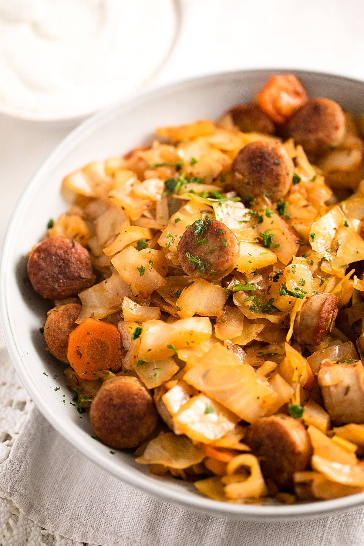 cabbage and kielbasa in a white bowl.