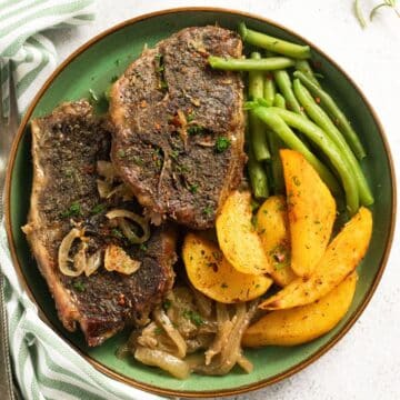 green plate with slow cooker lamb chops, roast potatoes and green beans.