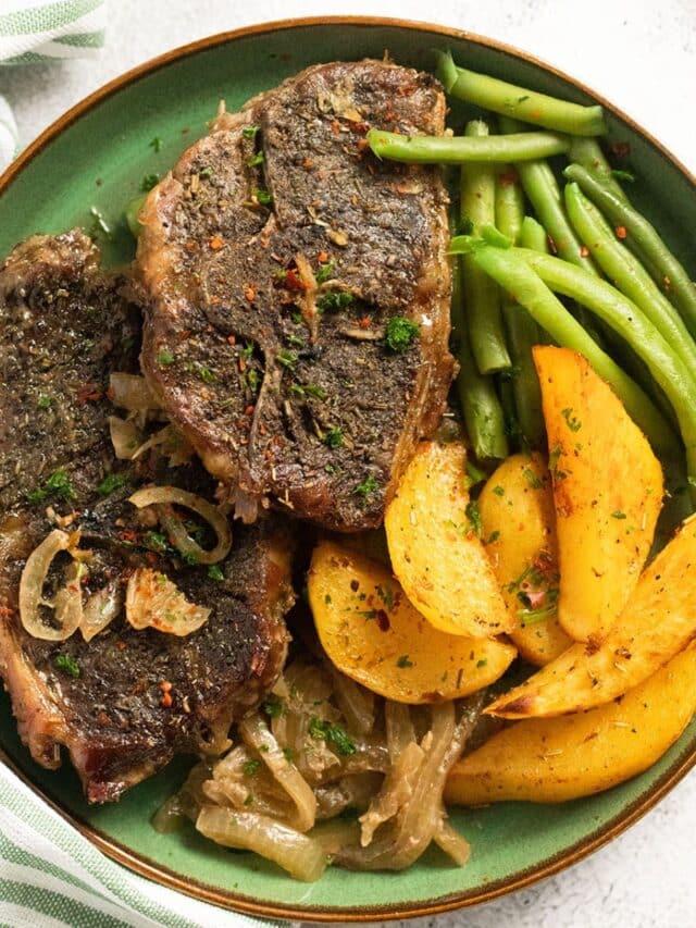green plate with slow cooker lamb chops, roast potatoes and green beans.