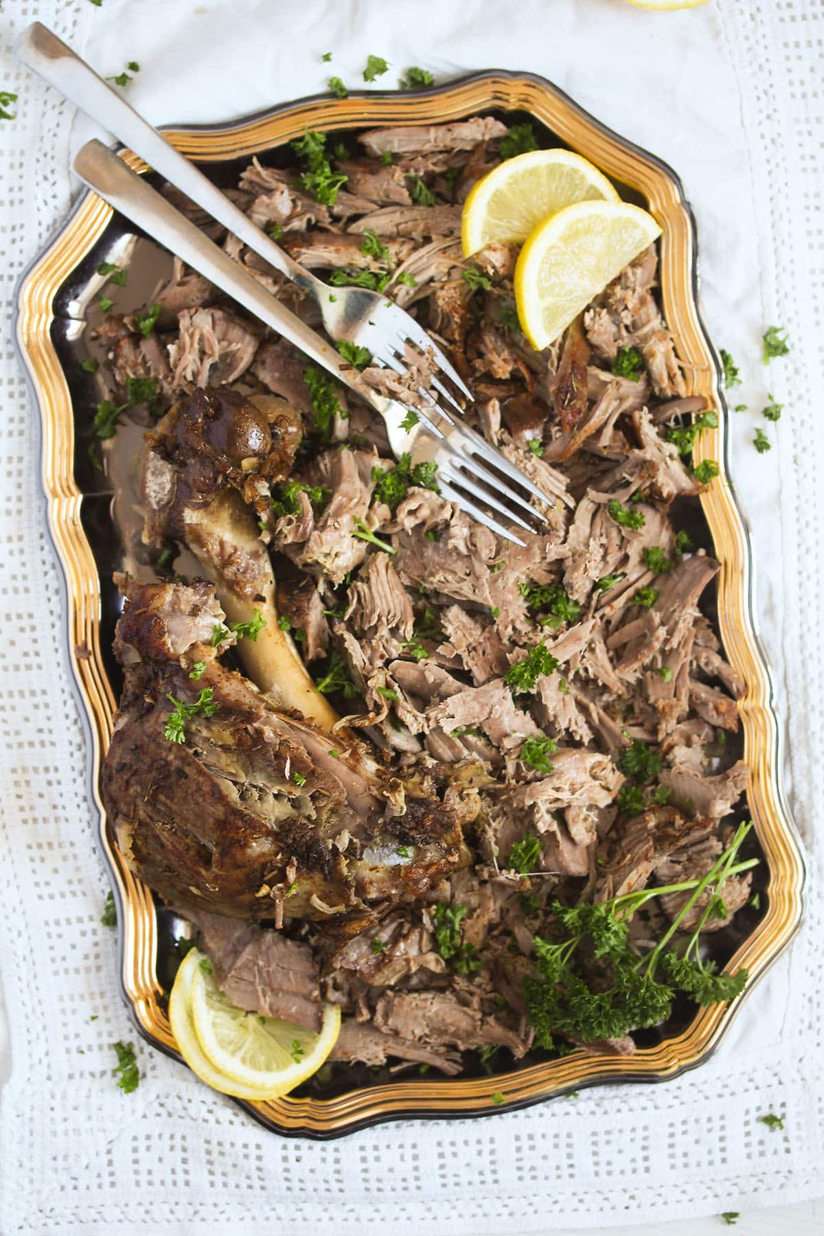 platter with slow cooked shredded lamb and a fork.
