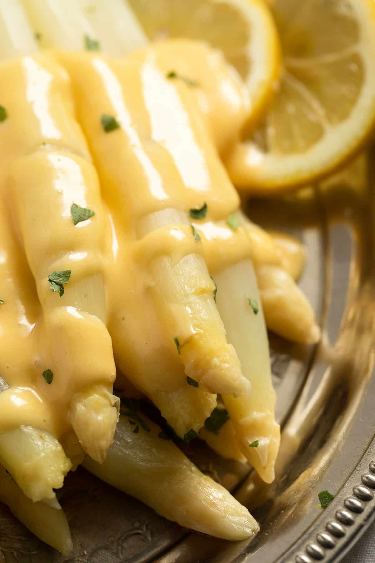 close up of white asparagus spears covered with creamy and glossy white sauce.