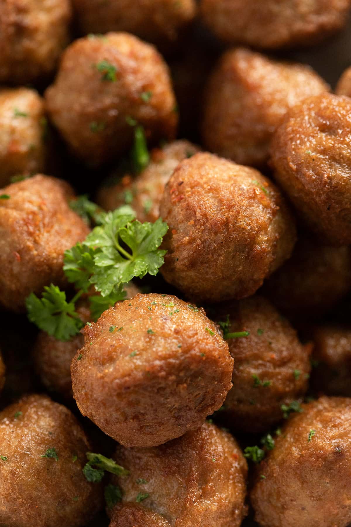 close up of cripspy small meatballs sprinkled with parsley.