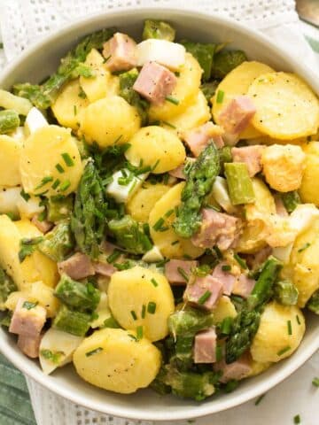 bowl full of potato asparagus salad with ham and eggs.