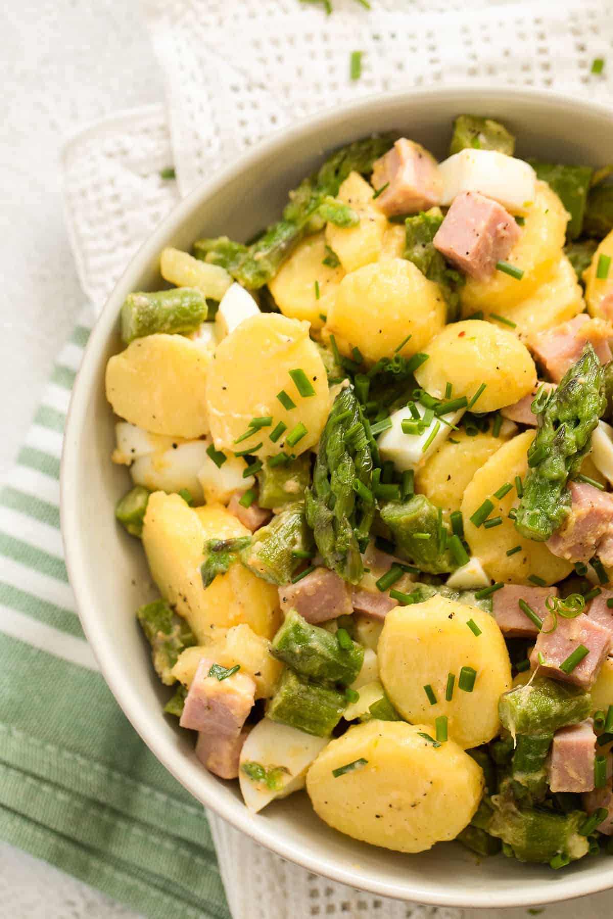 close up sliced potatoes, chopped asparagus, eggs and ham in a bowl.