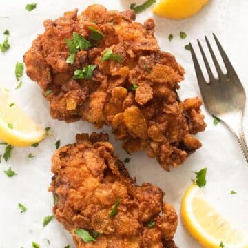 cornflake fried chicken served with lemon wedges and parsley.