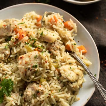 rice with chicken thighs, carrots and onions served with pickles.