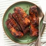 air fryer country style ribs served on a green plate with fork and knife.