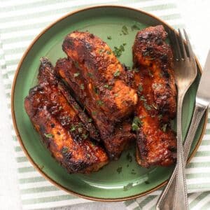 air fryer country style ribs served on a green plate with fork and knife.