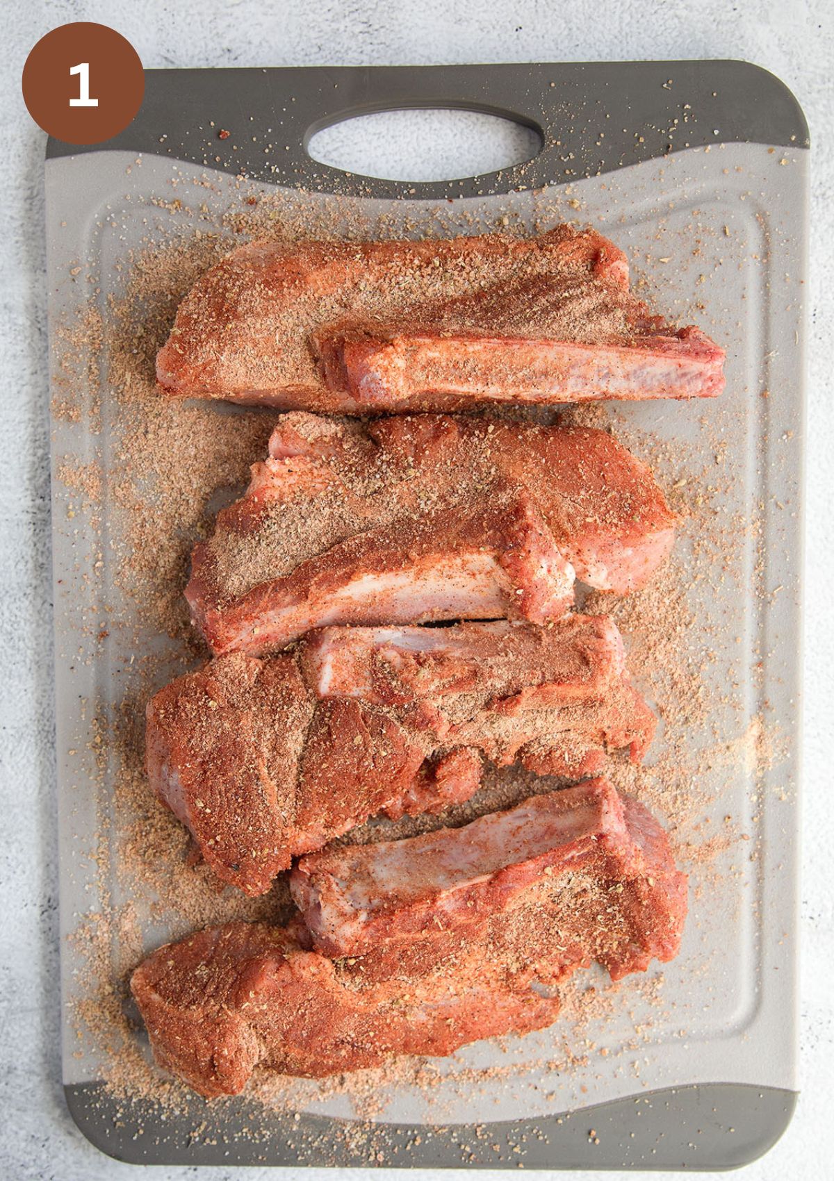 raw country style ribs rubbed with dry rub on a cutting board.