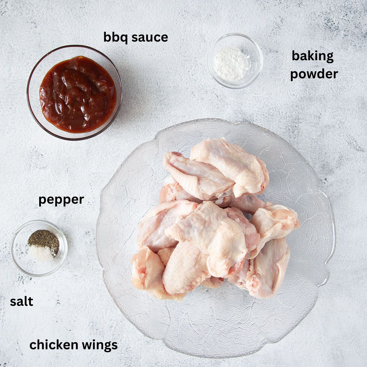 bowls with raw chicken wings ,barbecue sauce, salt, pepper and baking powder.