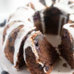 sliced bundt cake with sour cream and blueberries on a white round cutting board.