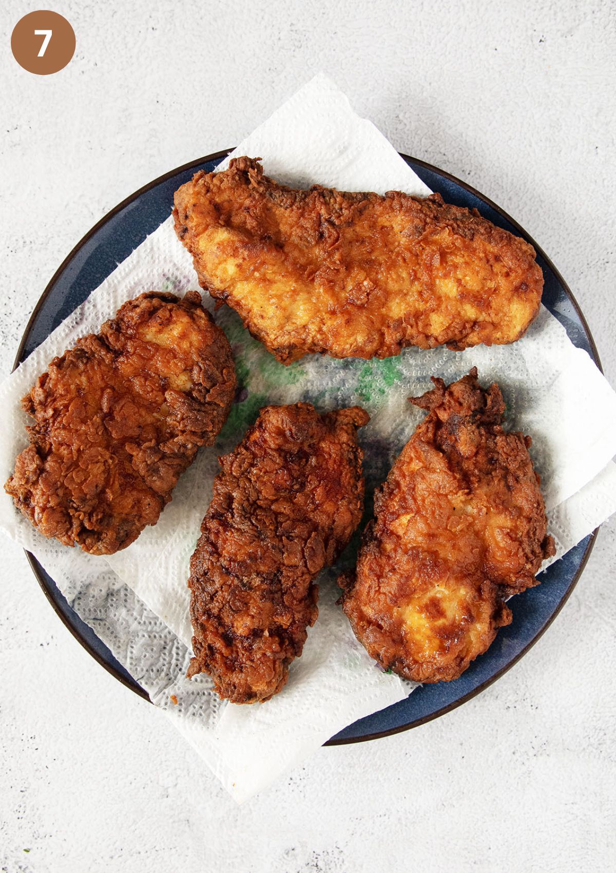 four pieces of fried chicken on a plate lined with paper to absorb the oil.