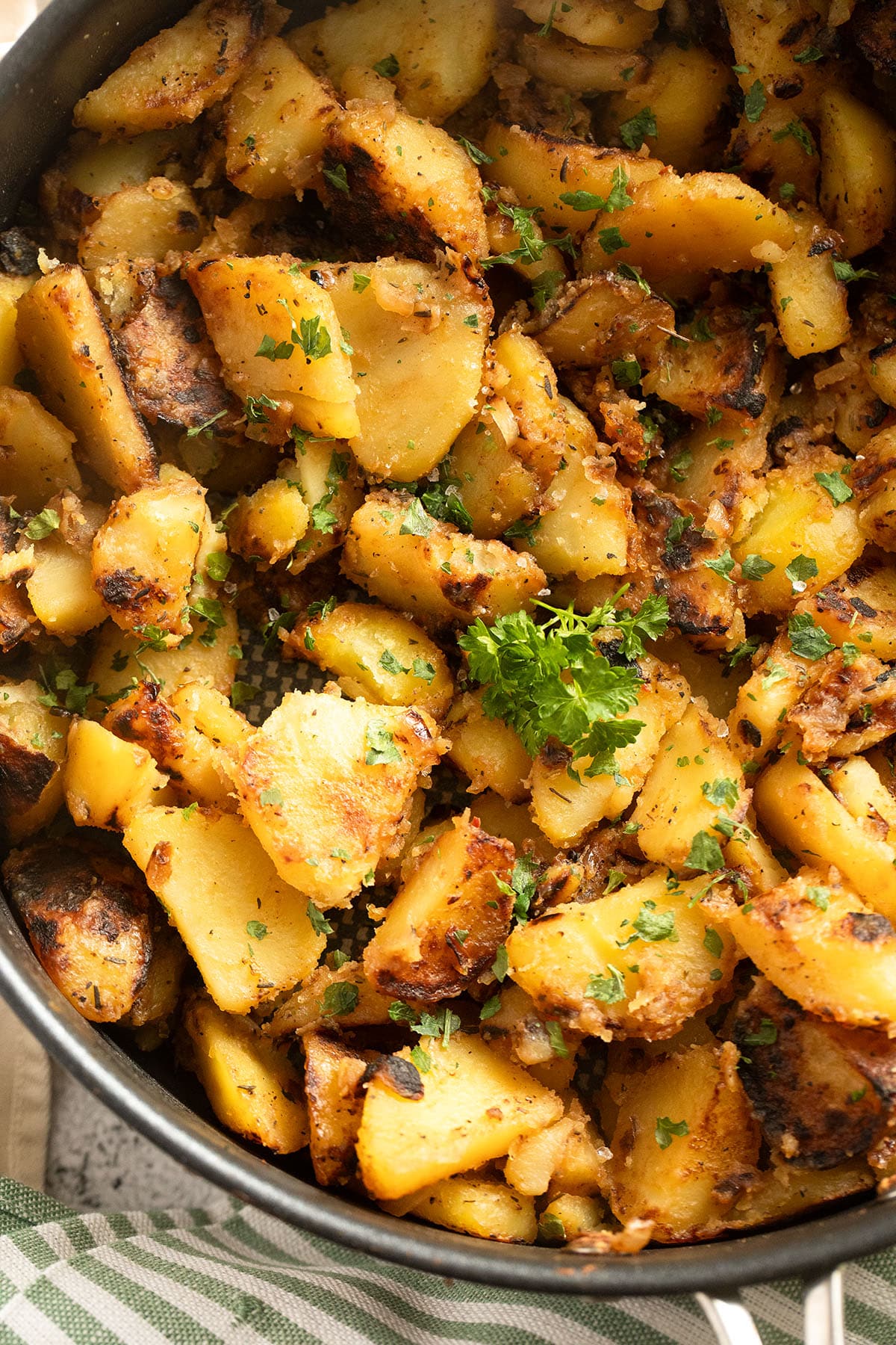 close up of potatoes fried in the pan with onions and sprinkled with parsley.