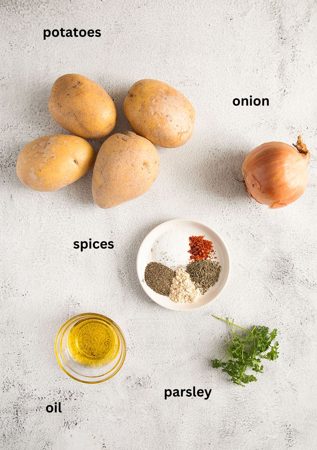 four raw potatoes, one onion, bowl with oil, spices and a sprig of parsley.