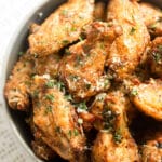 garlic parm wings in a bowl, sprinkled with parsley and cheese.