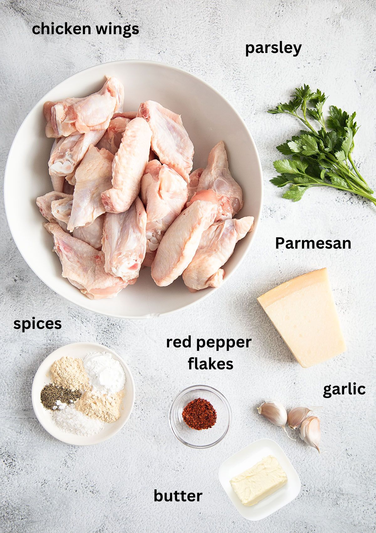 listed ingredients in bowls for making chicken wings with garlic butter and parmesan sauce.