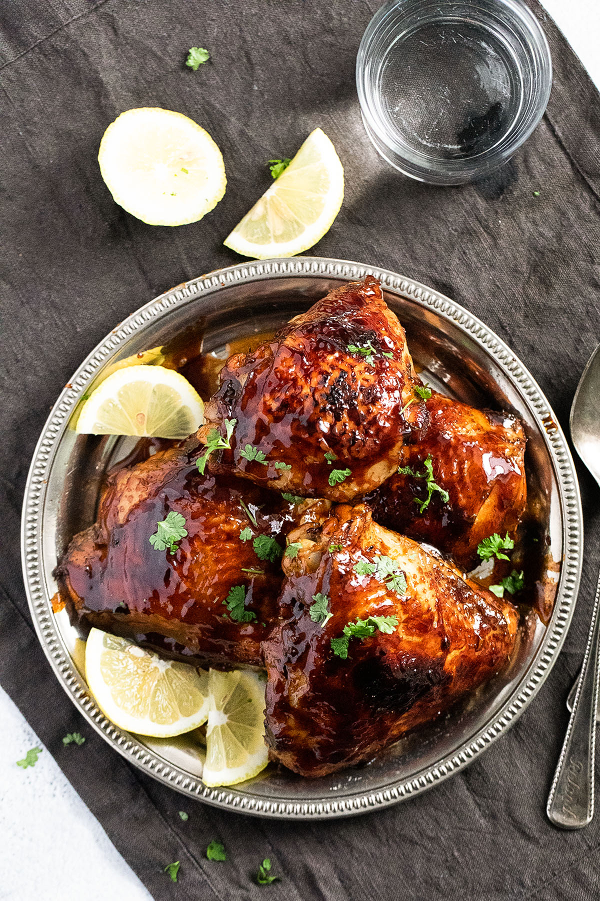 overhead view of a plate with honey baked thighs and lemon wedges.