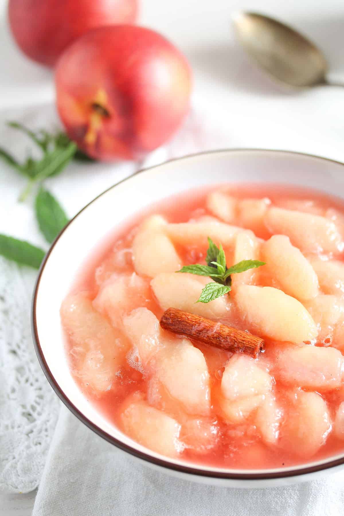 nectarine compote in a bowl and two nectarines behind it.