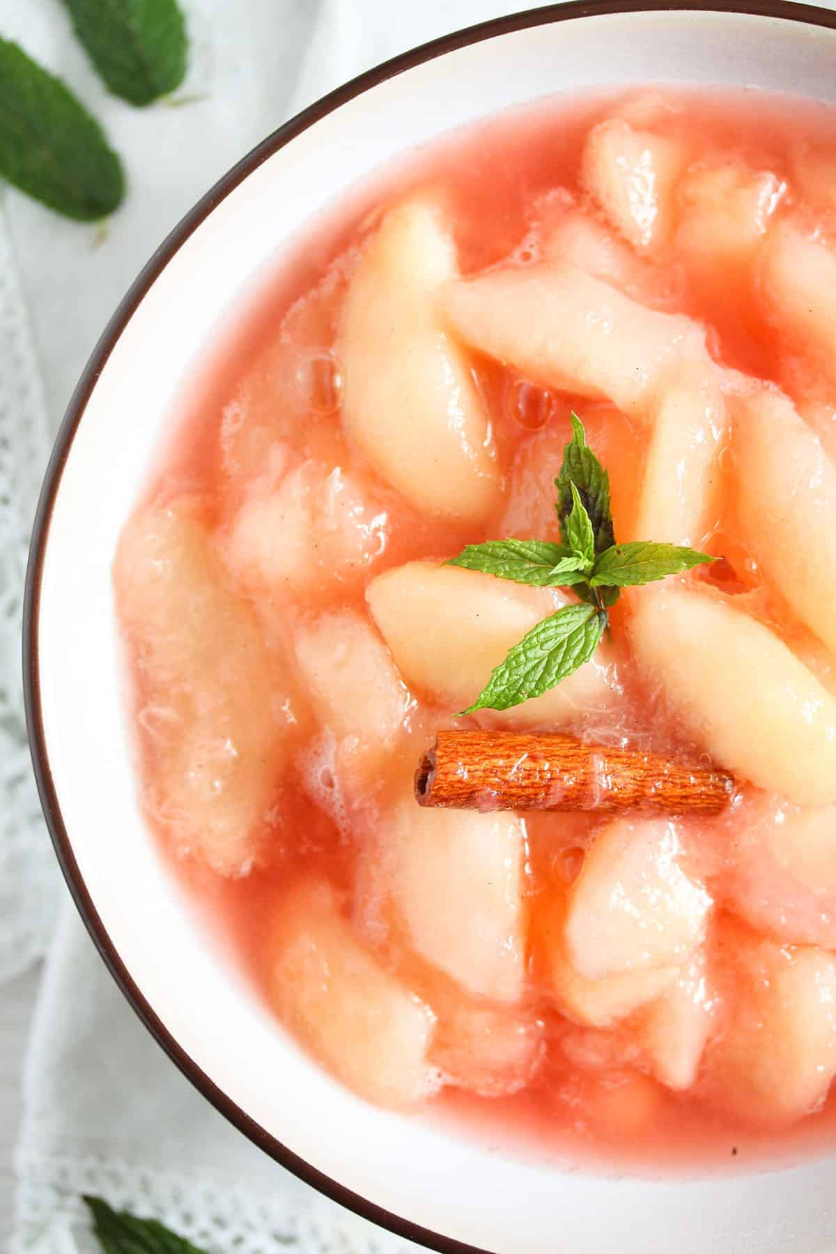 bowl with nectarine compote garnished with a cinnamon stick and mint.
