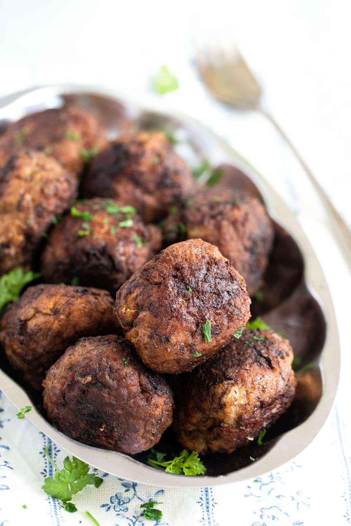 round meatballs made with pork and sprinkled with parsley.