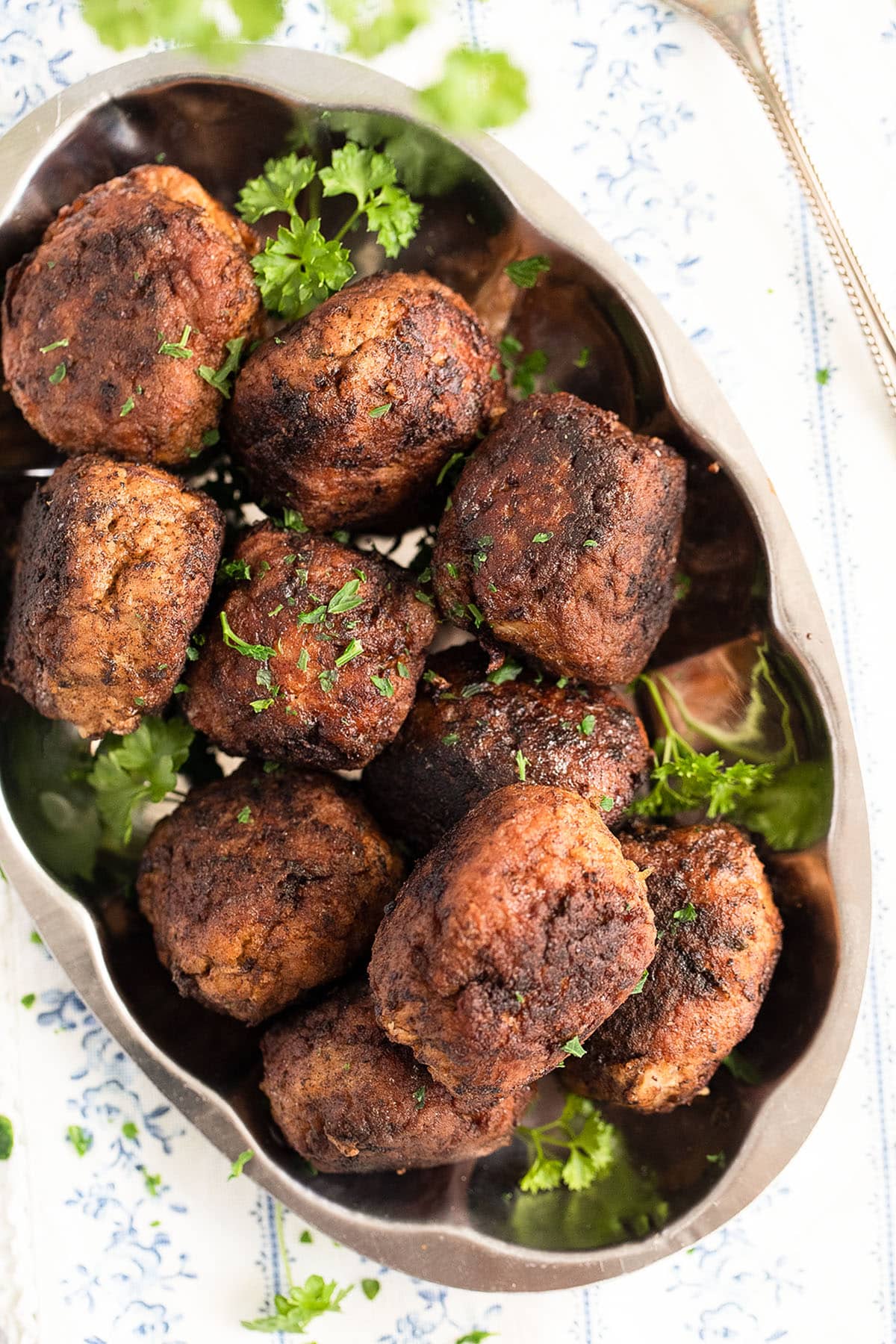 many meatballs made with ground pork on a vintage silver platter.