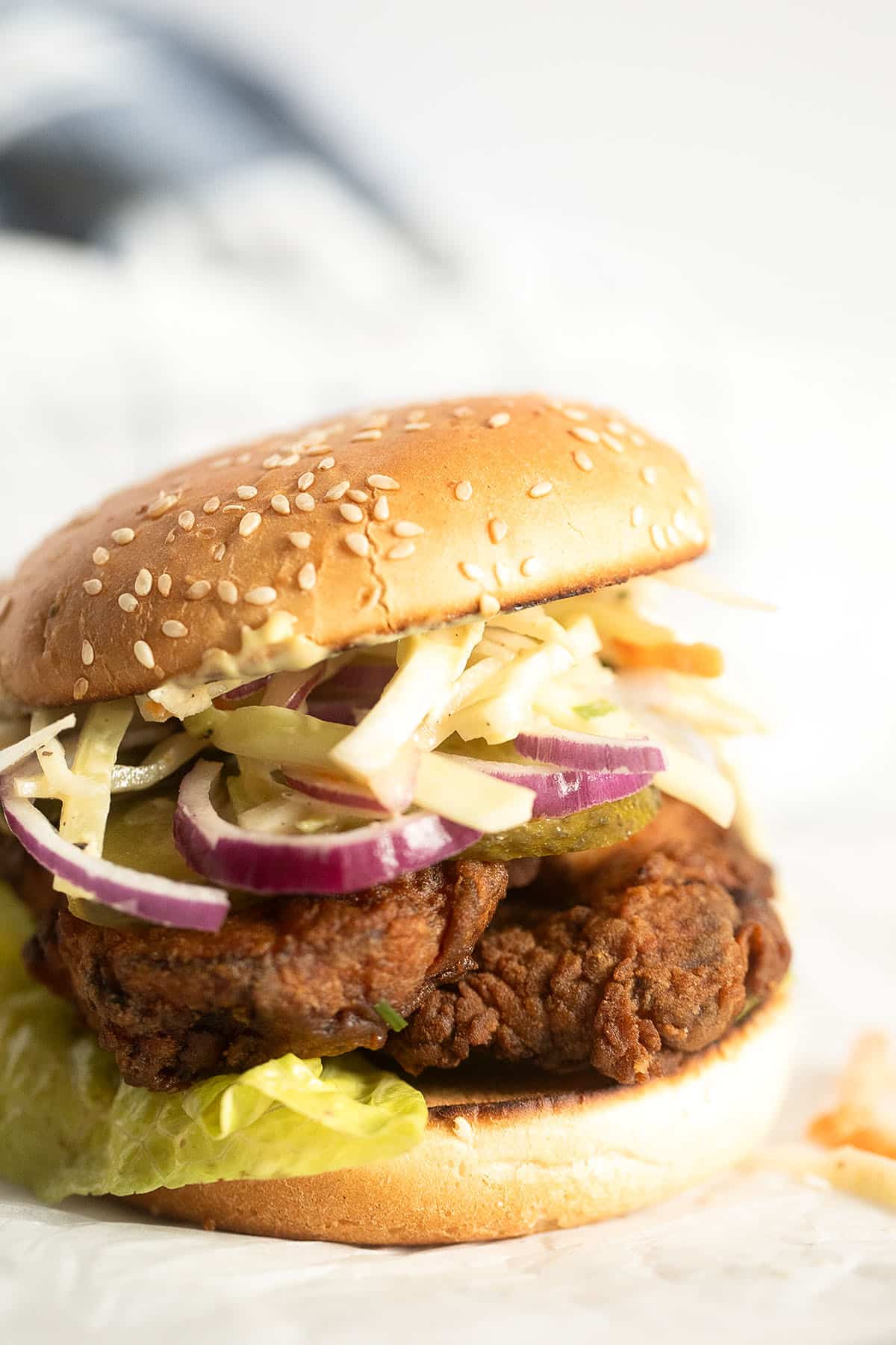 chicken burger with coleslaw, red onions and lettuce.
