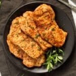 four air fryer thin pork chops on a black plate,