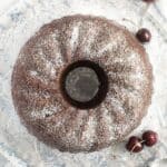 overhead view of a cherry chocolate bundt cake on a wire rack with three cherries around it.