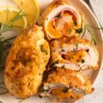 close up of two air fryer chicken cordon bleu, one sliced and showing the filling.