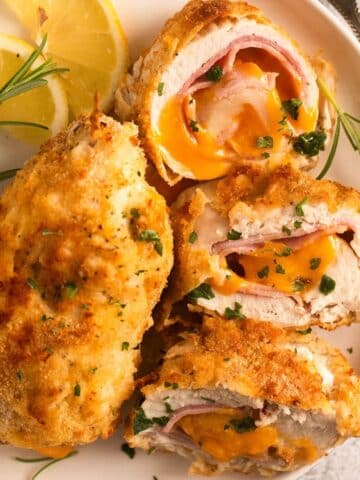 close up of two air fryer chicken cordon bleu, one sliced and showing the filling.
