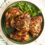cooked air fryer frozen chicken thighs on a green plate with parsley.