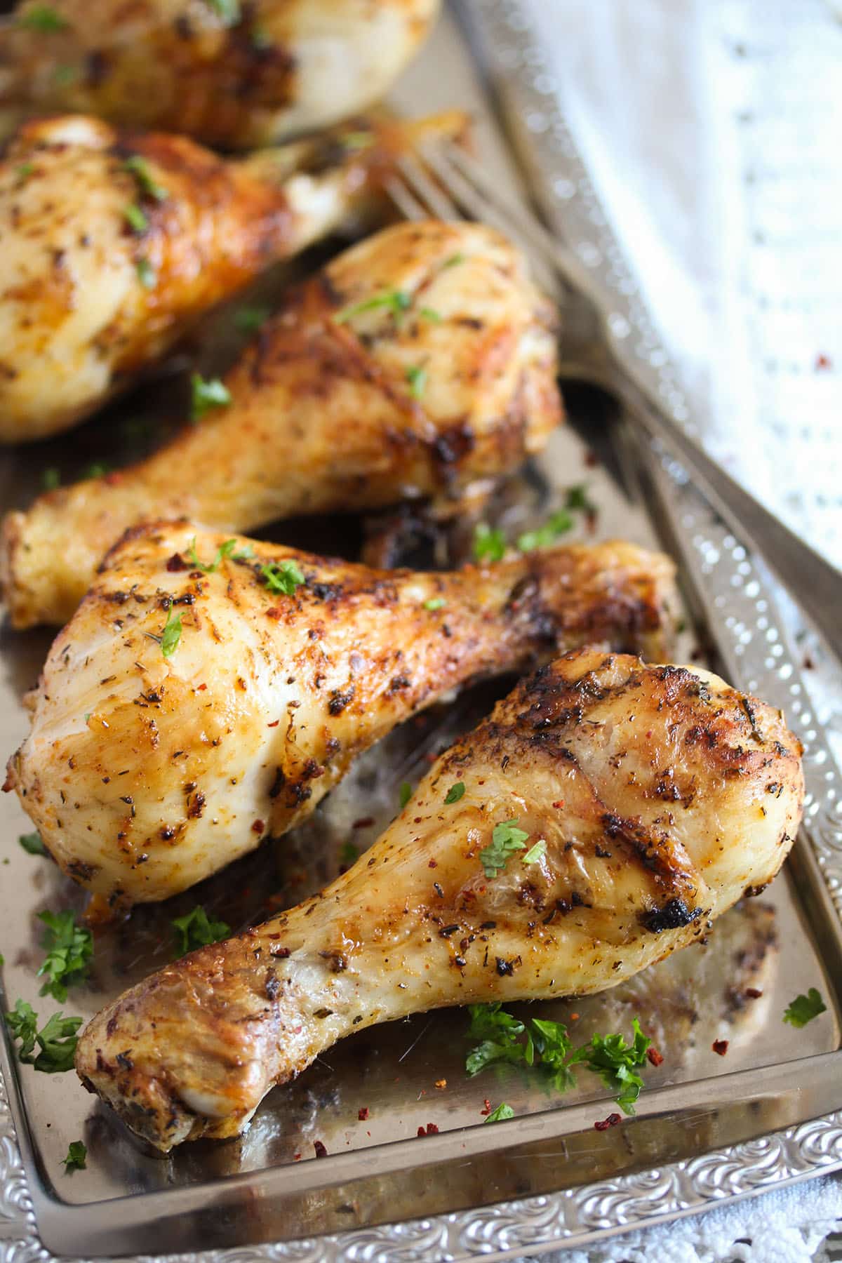 four golden brown chicken legs sprinkled with parsley.