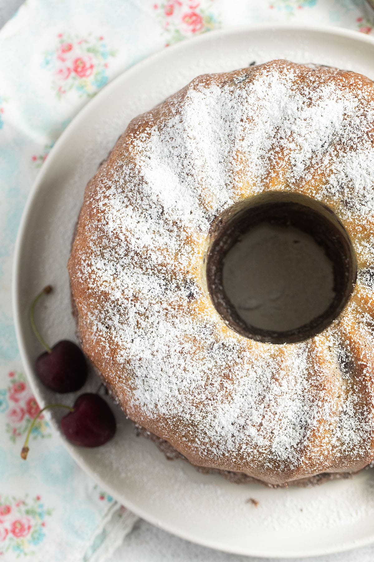 bundt cake with cherries sprinkled with powdered sugar.