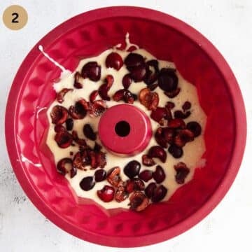 cake batter covered with cherries in a silicon bundt cake form.