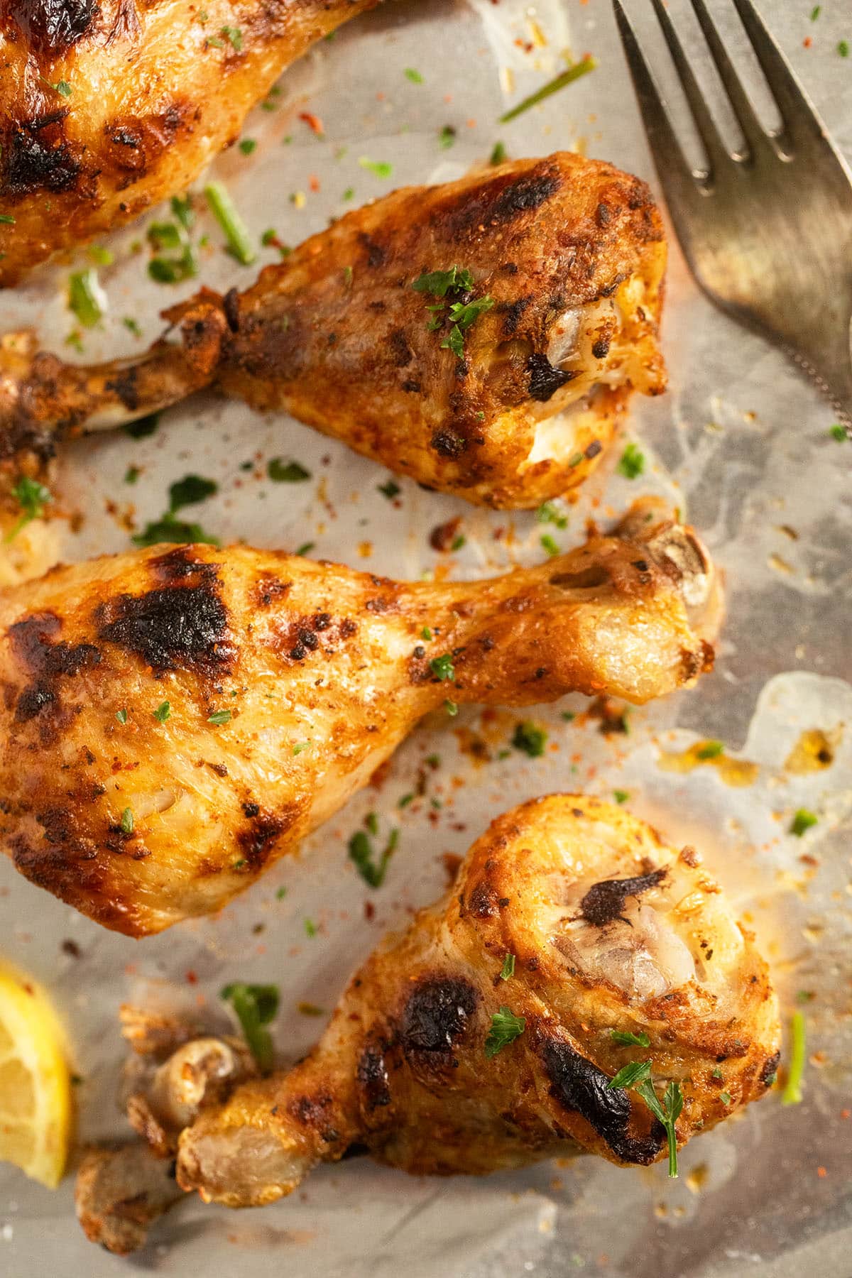 golden chicken legs with charred marks and a silver fork close up.