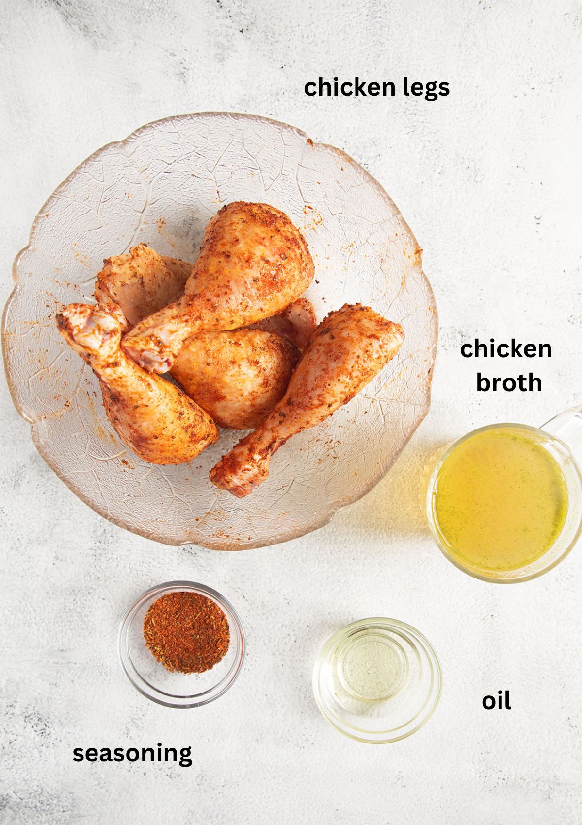 raw and seasoned drumsticks in a bowl and three other small bowls with broth, seasoning and oil.