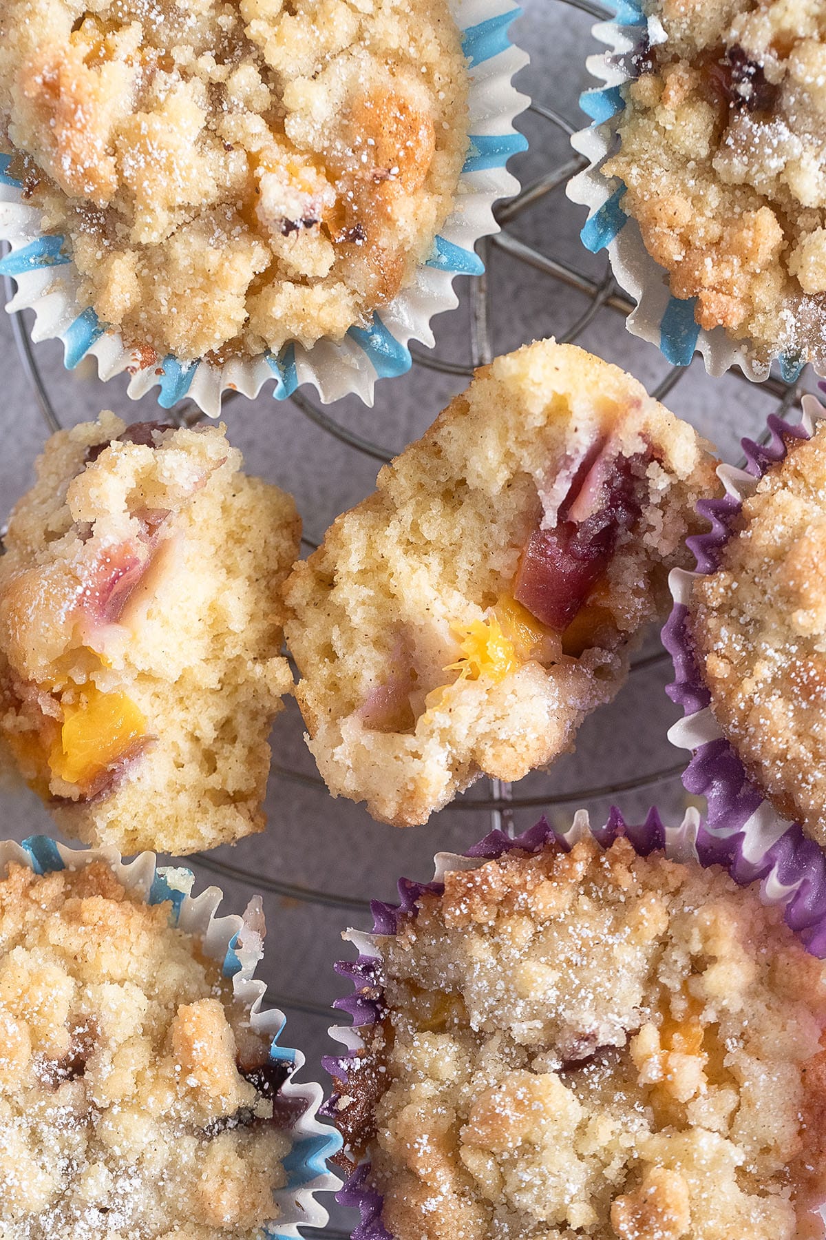 many muffins with crumble topping, one of them split in the middle.