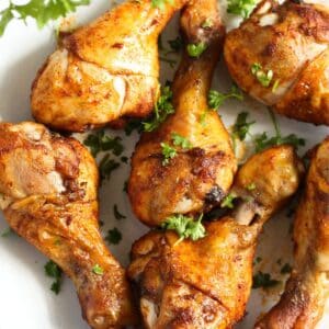 close up of many golden instant pot chicken drumsticks sprinkled with parsley.
