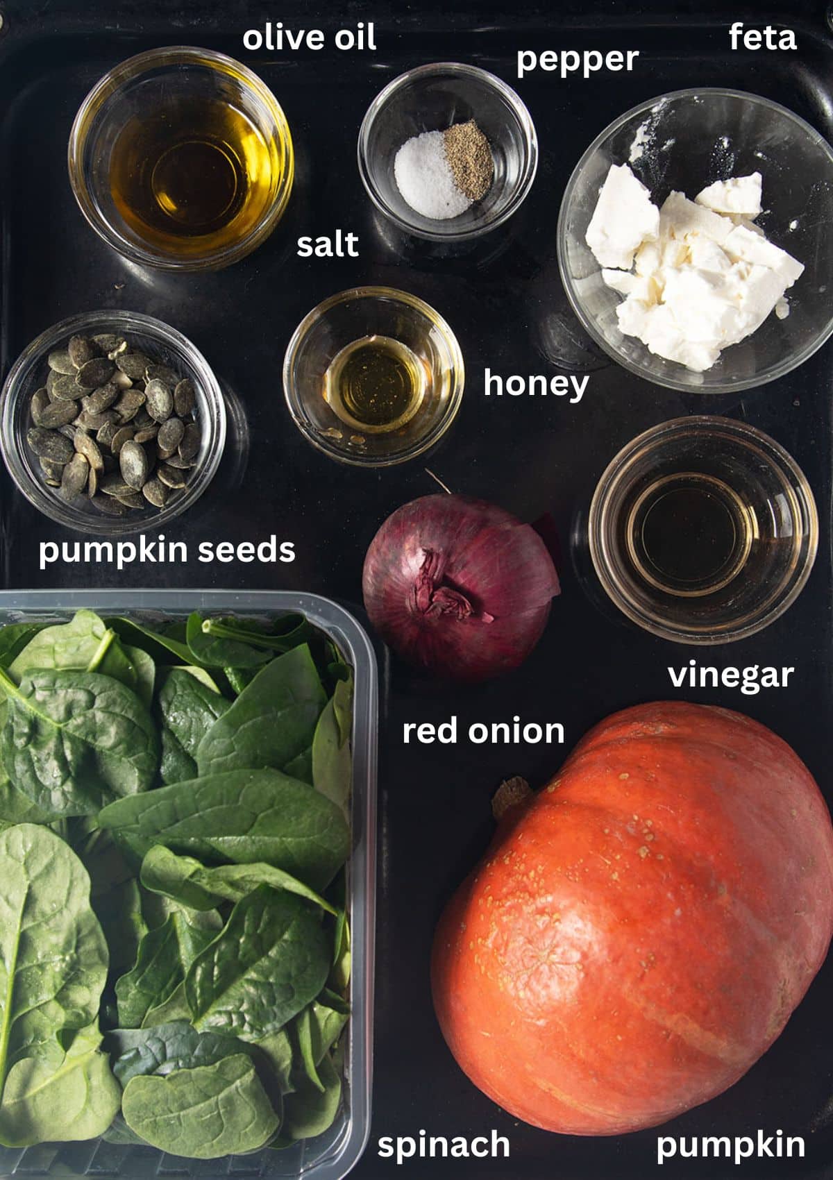 labeled ingredients for making salad with pumpkin, spinach, feta and pumpkin seeds.
