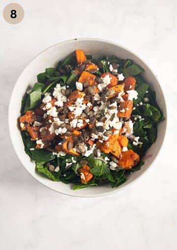 bowl with salad with spinach, roasted pumpkin, seeds, and feta.