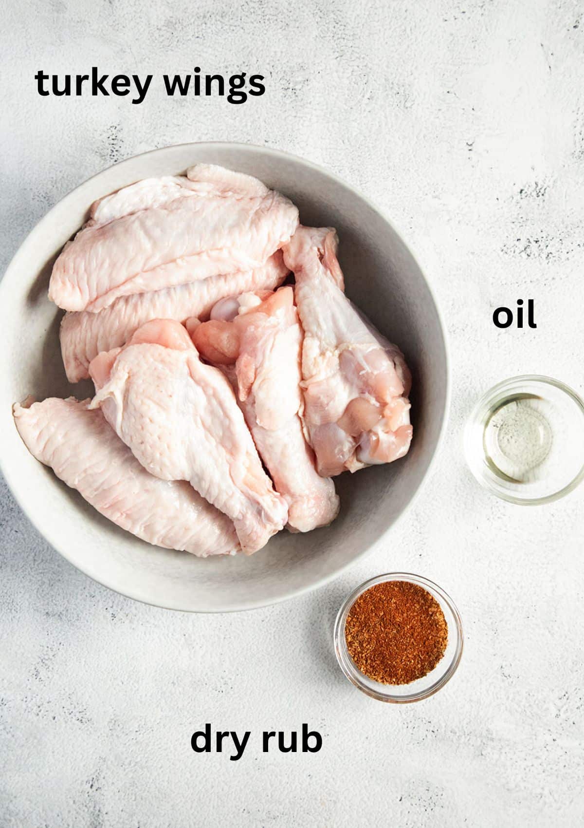 listed ingredients: fresh turkey wings, oil and dry rub in a bowl.