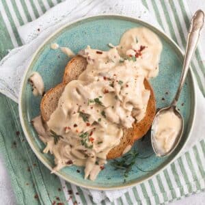 creamed turkey served o toast on a small blue plate with a spoon on it.