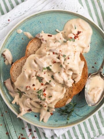 creamed turkey served o toast on a small blue plate with a spoon on it.
